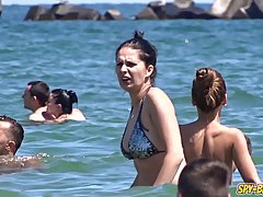 Nude women are sunbathing on the beach  while a horny voyeur is making...